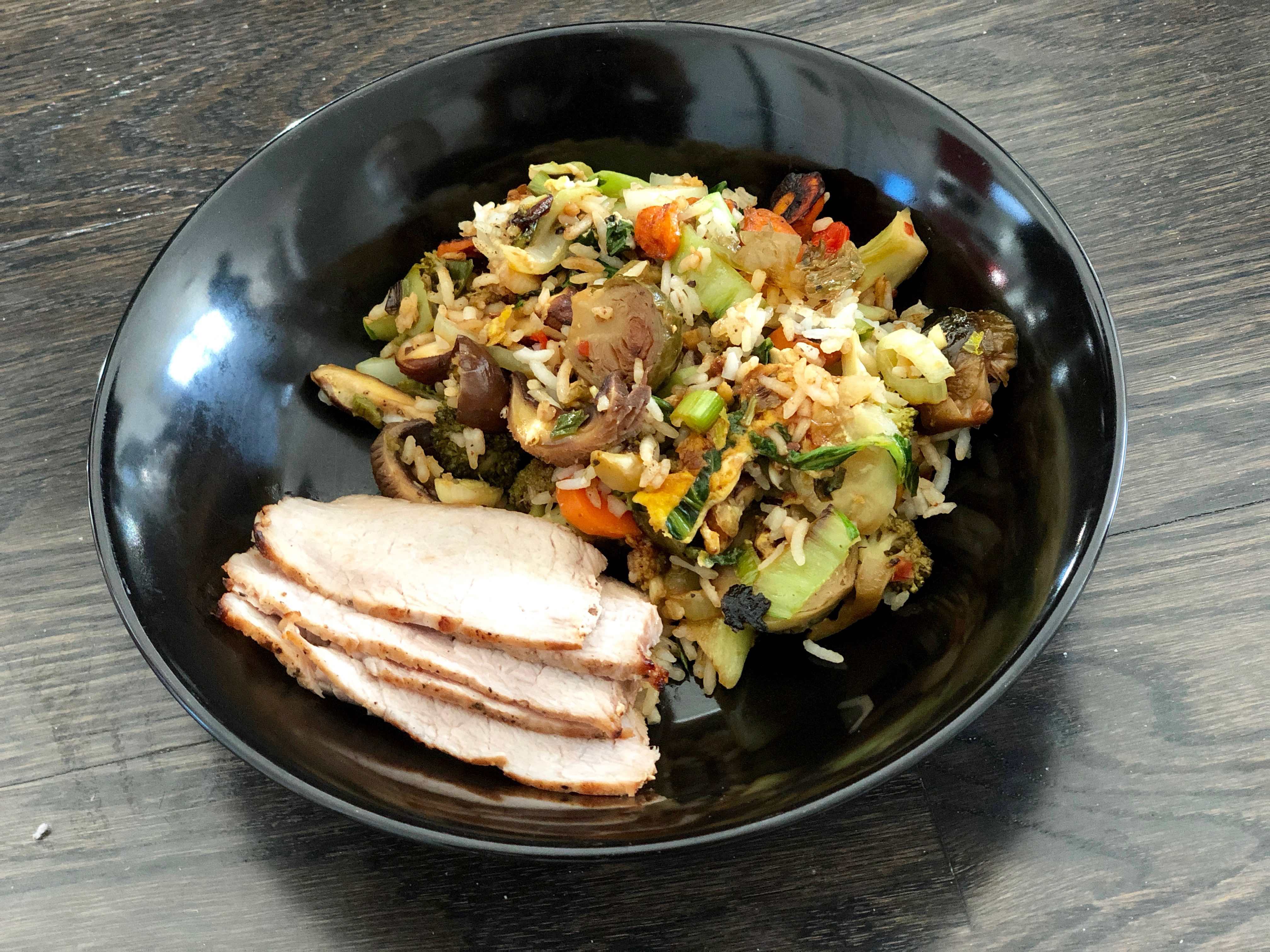 Vegetable fried rice with pork in black bowl