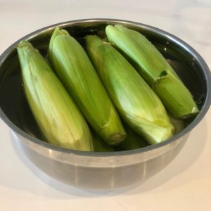 Here's a super easy "recipe" for cooking corn-on-the-cob on the grill. This is my preferred method because the corn cooks right in the husks, eliminating most of the mess that comes from shucking.  You shuck the corn AFTER it is cooked, and it's less messy because the silk slides right off with the corn husk. | www.amiofbs.com